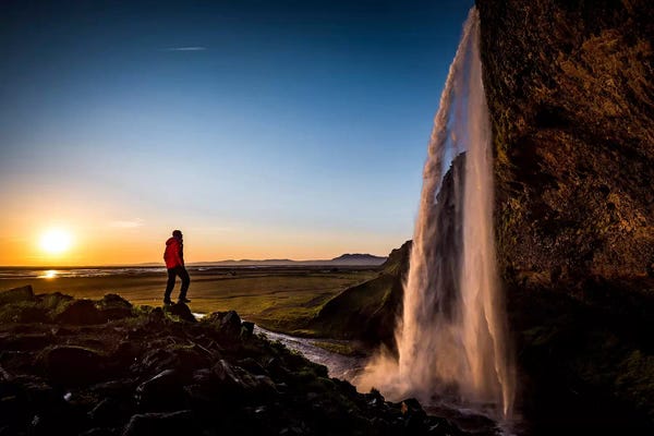Exploration: A Lone Figure In Front Of Seljalandfoss, Sudurland, Iceland, At Midnight by Alex Buisse