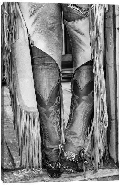 Horse drive in winter on Hideout Ranch, Shell, Wyoming. Cowgirl detail of boots and chaps in doorway of log cabin. Canvas Art Print - Boots
