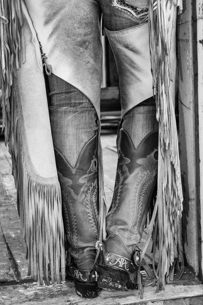 Wyoming: Horse drive in winter on Hideout Ranch, Shell, Wyoming. Cowgirl detail of boots and chaps in doorway of log cabin. by Darrell Gulin