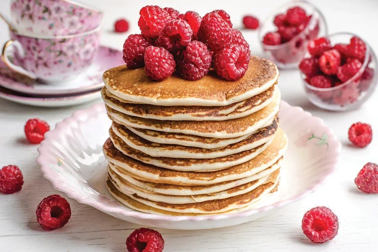 A Stack Of Pancakes Topped With Raspberries