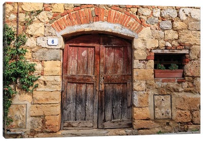 Italy, Monteriggioni. Stone wall, wooden door with planted geraniums. Canvas Art Print