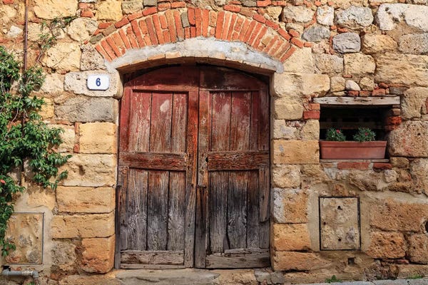 Italy, Monteriggioni. Stone wall, wooden door with planted geraniums.
