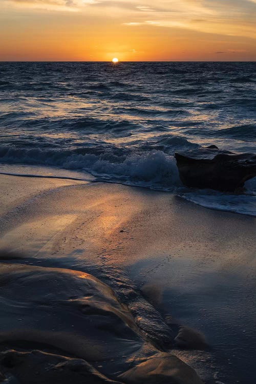 Sun setting on the Pacific Ocean with reflection of golden in the sand