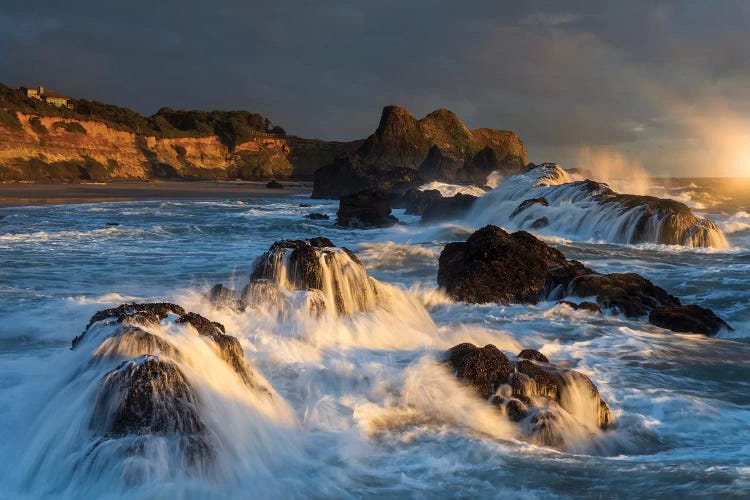 Waves crashing on rocks and washing down the sides at sunset