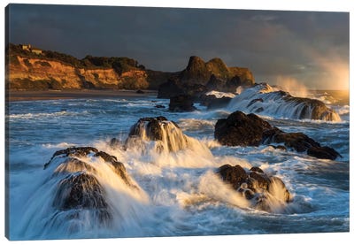 Waves crashing on rocks and washing down the sides at sunset Canvas Art Print