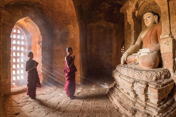 Buddhism: Two Young Novice Monks Praying To Buddha In An Old Temple In Bagan, Myanmar by Jan Becke