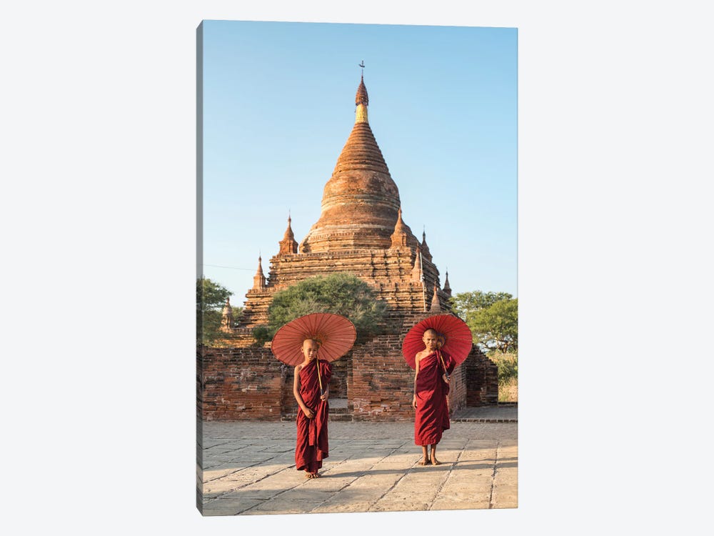 Two Young Novice Monks With Red Umbrellas Standing In Front Of A Temple, Bagan, Myanmar by Jan Becke 1-piece Canvas Wall Art
