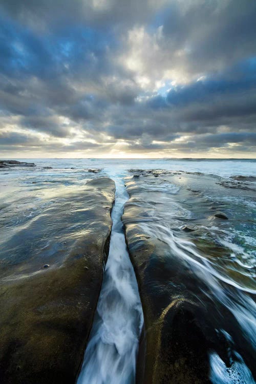 USA, California, La Jolla. Wave flows through cracked sandstone.