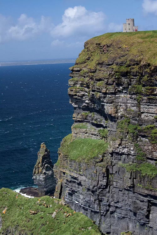 Scenic Cliffs Of Moher And O'Brien's Tower Under A Blue Sky And White Puffy Clouds With Waves Of The Atlantic Ocean Below