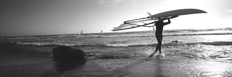 Man carrying a surfboard over his head on the beach, Santa Cruz, California, USA