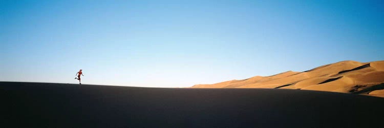 Low angle view of a woman running in the desert 2, Great Sand Dunes National Monument, Colorado, USA