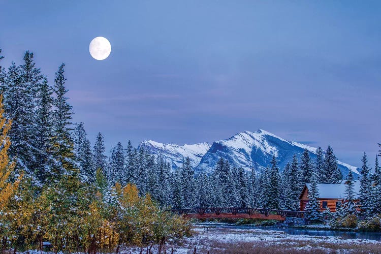 Moon over Pigeon Mountain and log cabin in forest and bridge near Policemans Creek, Canmore, Alberta, Canada