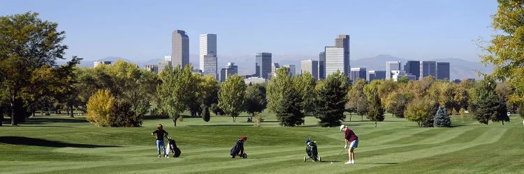 Four people playing golf with buildings in the background, Denver, Colorado, USA