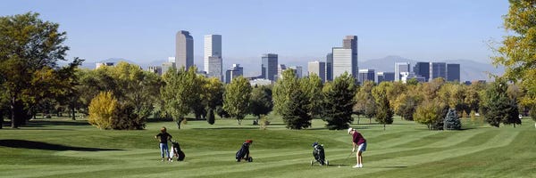 Golf Courses: Four people playing golf with buildings in the background, Denver, Colorado, USA by Panoramic Images