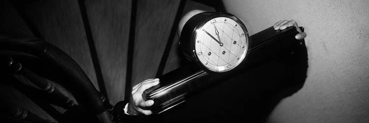 Man Carrying Clock Up Stairs on Shoulders