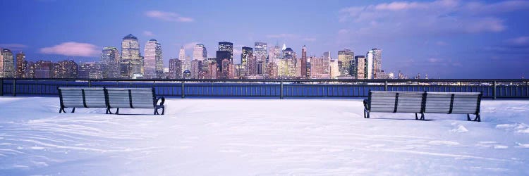 Park benches in snow with a city in the background, Lower Manhattan, Manhattan, New York City, New York State, USA