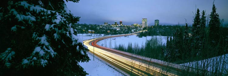 Autumobile lights on busy street, distant city lights, frozen Westchester Lagoon, Anchorage, Alaska, USA.