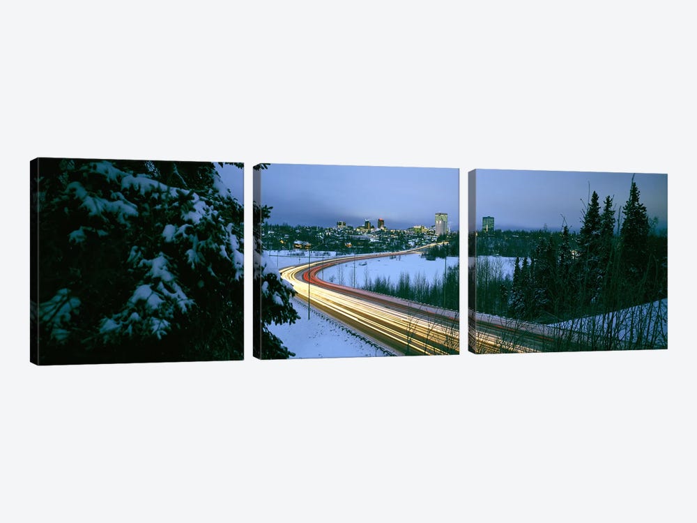 Autumobile lights on busy street, distant city lights, frozen Westchester Lagoon, Anchorage, Alaska, USA. by Panoramic Images 3-piece Canvas Art Print