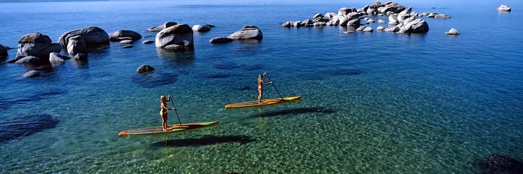 Two women paddle boarding in a lake, Lake Tahoe, California, USA