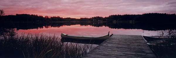 Canoes: Canoe tied to dock on a small lake at sunset, Sweden by Panoramic Images