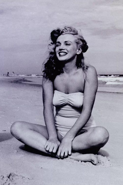 A Young, Smiling Marilyn Monroe Sitting On The Beach