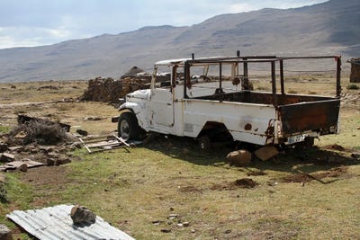 Broken Car, Surrounded By Material, Used To Built The Rondavels - Sani Pass, Lesotho, Southern Africa by Ramona Heiner framed canvas print