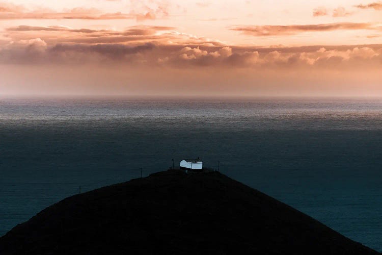 Lone House On A Hill Looking Over The Ocean Onto An Epic Sunset