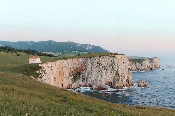 Coastal Cliff With A Small House During Sunset