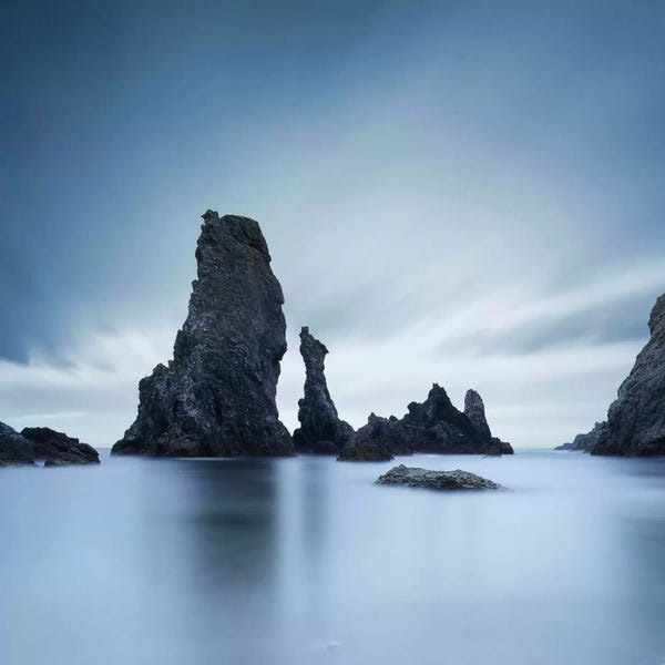 Dark rocks in a blue ocean under cloudy sky in a bad weather.