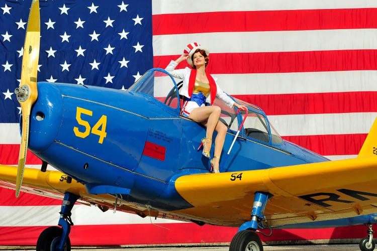 Patriotic American Pin-Up Girl Tipping Her Hat While Posing With A PT-19 Vintage Aircraft