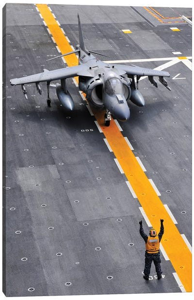 Airman Directs An AV-8B Harrier II Aircraft On The Flight Deck Of USS Peleliu Canvas Art Print - Aircraft Carriers