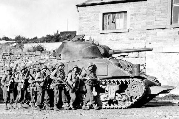Soldiers And Their Tank Advance Into A Belgian Town During WWII