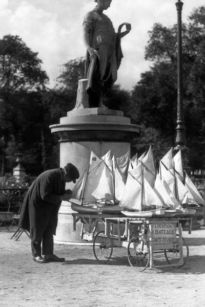 Salespeople: 1930s Paris France Tuileries Gardens Man With Cart Of Miniature Toy Sailboats For Rent by Vintage Images
