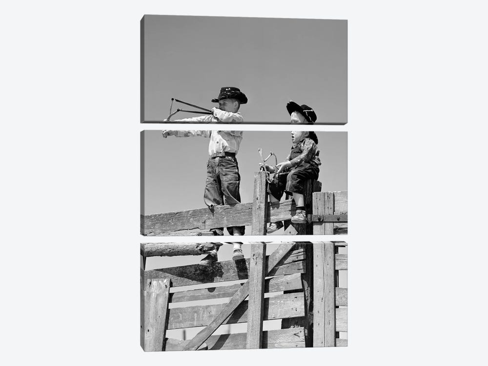 1950s Two Young Boys Dressed As Cowboys Shooting Slingshots On Top Of Wooden Fence Outdoor by Vintage Images 3-piece Canvas Art Print