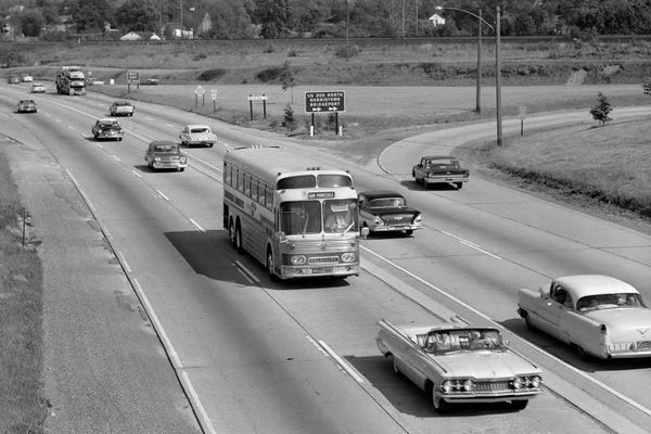 1960s Overhead Of Busy Four Lane Undivided Highway With Convertible Car And Long Haul Passenger Bus Approaching Camera