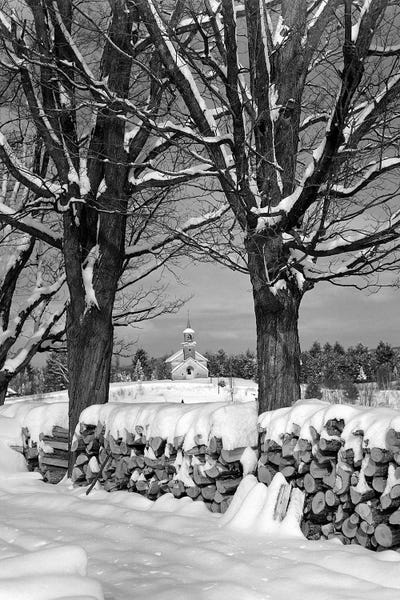 1940s Pile Of Snow-Covered Firewood Logs Stacked Between Two Trees With Country Church In Background
