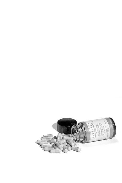 1950s Pill Bottle On Its Side Next To Pile Of Capsules