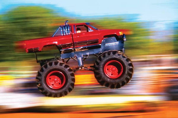 Vintage Images: Big Wheeled Red Truck Jumping Blurred Background by Vintage Images