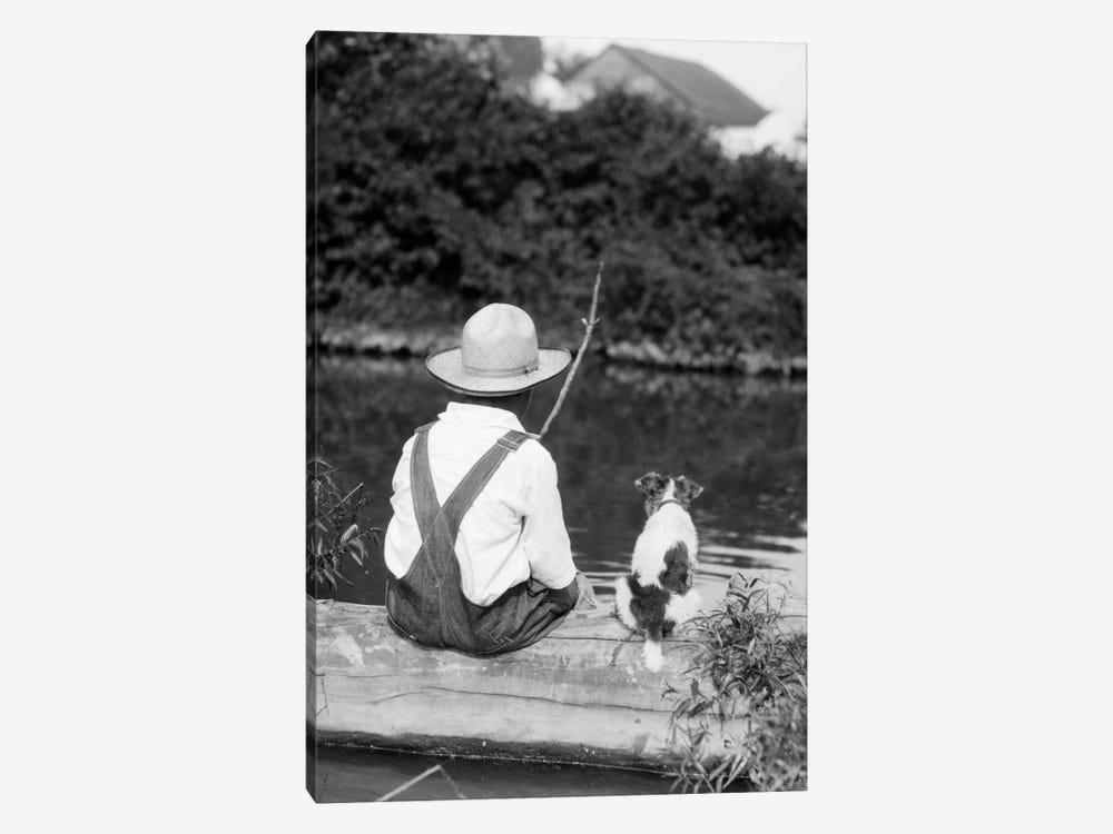 1920s-1930s Farm Boy Wearing Straw Hat And Overalls Sitting On Log With Spotted Dog Fishing In Pond by Vintage Images 1-piece Canvas Art Print