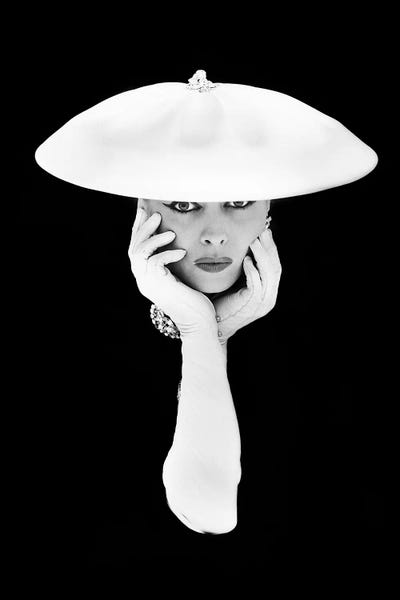 Fashion Photography: 1950s Glamorous Woman Long White Gloves And Hat Against Dark Background Looking At Camera by Vintage Images