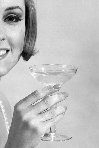 Black & White Pop Culture Art: 1960s Smiling Woman Wearing Pearls Offering A Toast Looking At Camera by Vintage Images