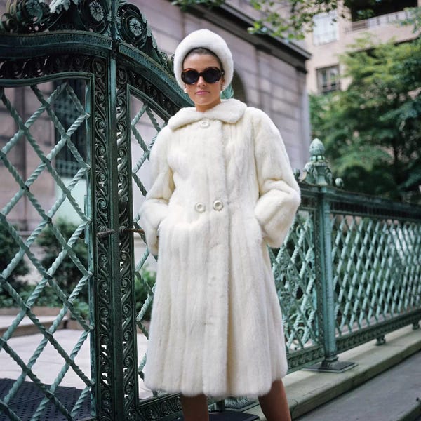 1960s Woman Wearing White Fur Coat Hat Sunglasses By Wrought Iron Gate Clothes