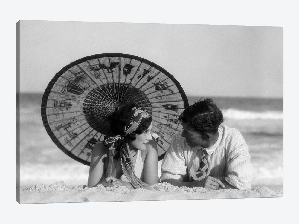 1920s Romantic Couple Man Woman Looking At One Another Lying Face To Face Under Oriental Parasol On Sandy Beach by Vintage Images 1-piece Art Print