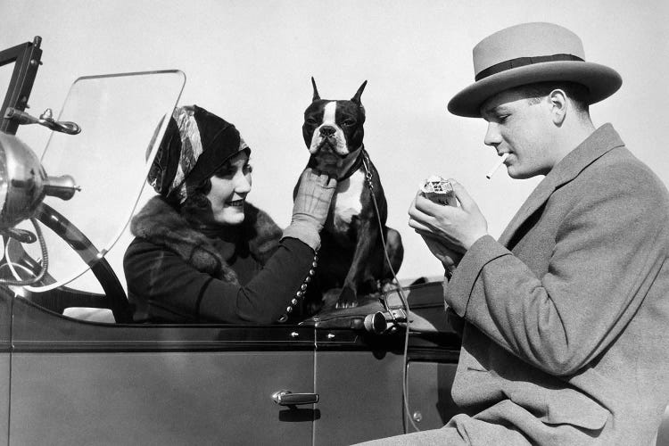 1920s Woman Sitting In Driver's Seat Convertible Car With Boxer Dog Man Lighting Cigarette