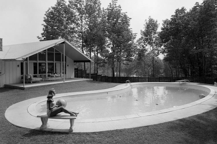 1950s 1960s Blond Woman Bathing Suit Sitting On Stone Bench Beach Ball Near Kidney Shaped Swimming Pool