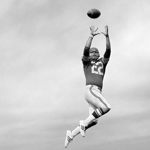Action Shots: 1970s Player Jumping To Catch Football Pass by Vintage Images
