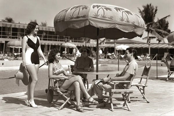 Miami Beach: 1930s 1940s 3 Women Bathing Suits Single Man Casual Clothes Sitting Talking Under Pool Side Umbrella Miami Beach Florida USA by Vintage Images