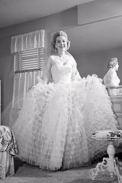 1950s 1960s Smiling Woman Looking At Camera By Bedroom Mirror Dressed In Formal Attire Ruffled Evening Gown