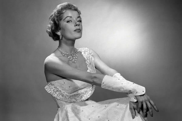 Historical Fashion: 1950s Portrait Of Woman Dressed In Evening Gown With Beaded Cuffs And Jewelry With A Haughty Facial Expression Looking At Camera by Vintage Images