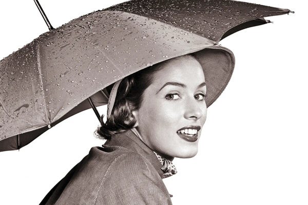 Rain: 1950s Smiling Woman Looking At Camera Under An Umbrella Wearing Raincoat And Hat by Vintage Images